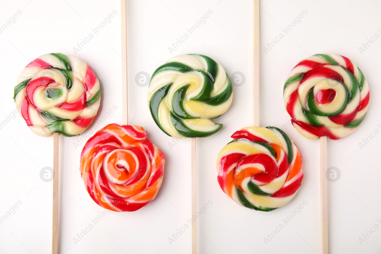 Photo of Many colorful lollipops on white background, flat lay