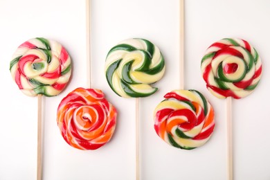 Photo of Many colorful lollipops on white background, flat lay