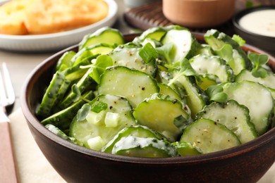 Photo of Bowl of delicious cucumber salad on table, closeup