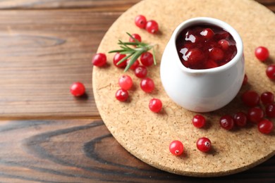 Photo of Cranberry sauce, fresh berries and rosemary on wooden table, space for text