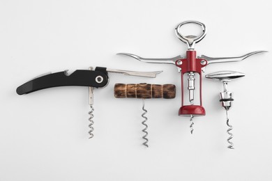 Different corkscrews on white background, flat lay