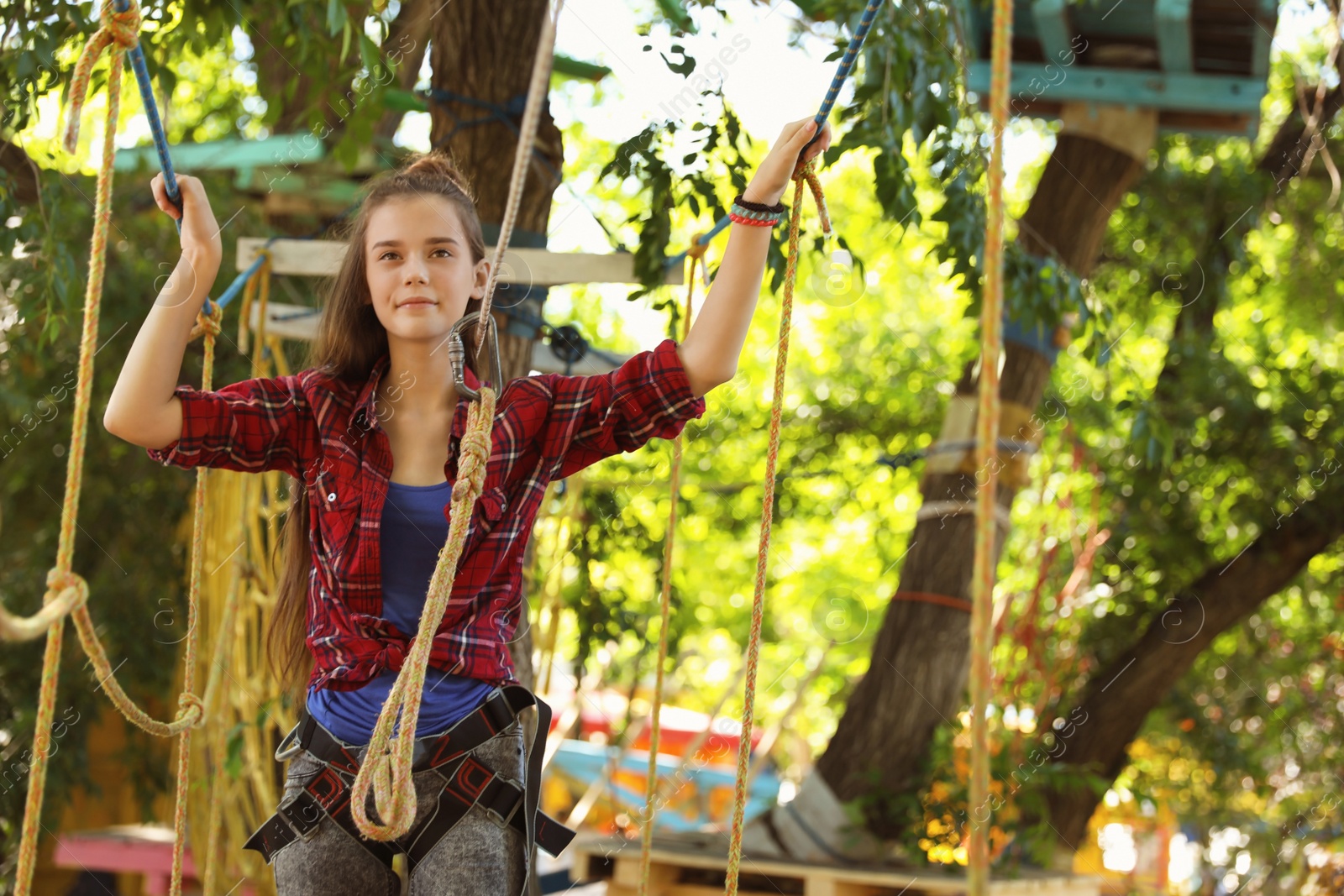 Photo of Teenage girl climbing in adventure park. Summer camp