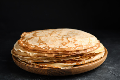 Stack of fresh thin pancakes on black table