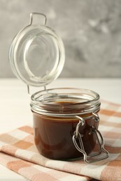 Photo of Tasty barbecue sauce in glass jar on table, closeup