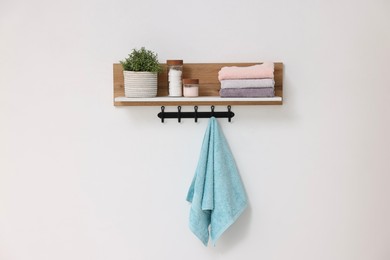Photo of Clean towels, houseplant and toiletries on shelf indoors