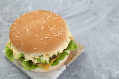 Delicious cheeseburger on grey textured table, closeup. Space for text