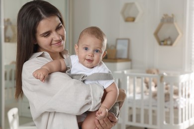 Photo of Happy young mother with her baby in nursery. Space for text