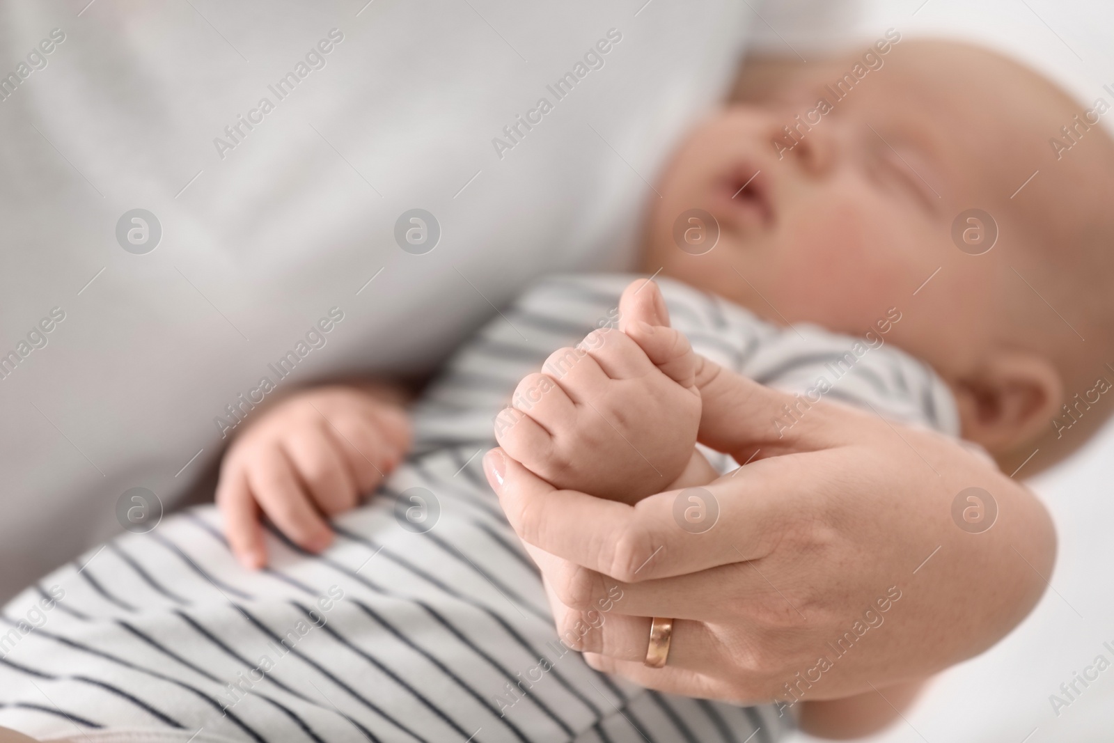 Photo of Mother holding her cute sleeping baby, focus on hands