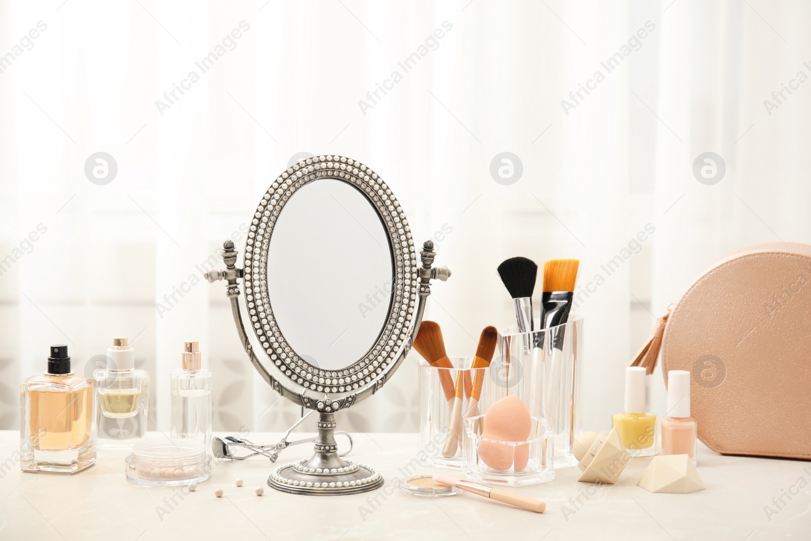 Photo of Mirror in antique frame and different cosmetics on dressing table. Beauty blogger