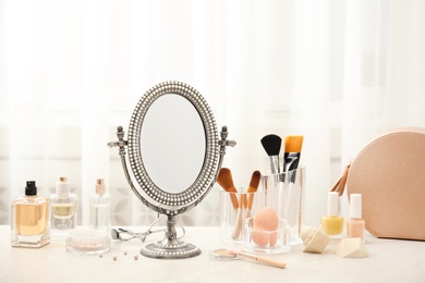 Mirror in antique frame and different cosmetics on dressing table. Beauty blogger