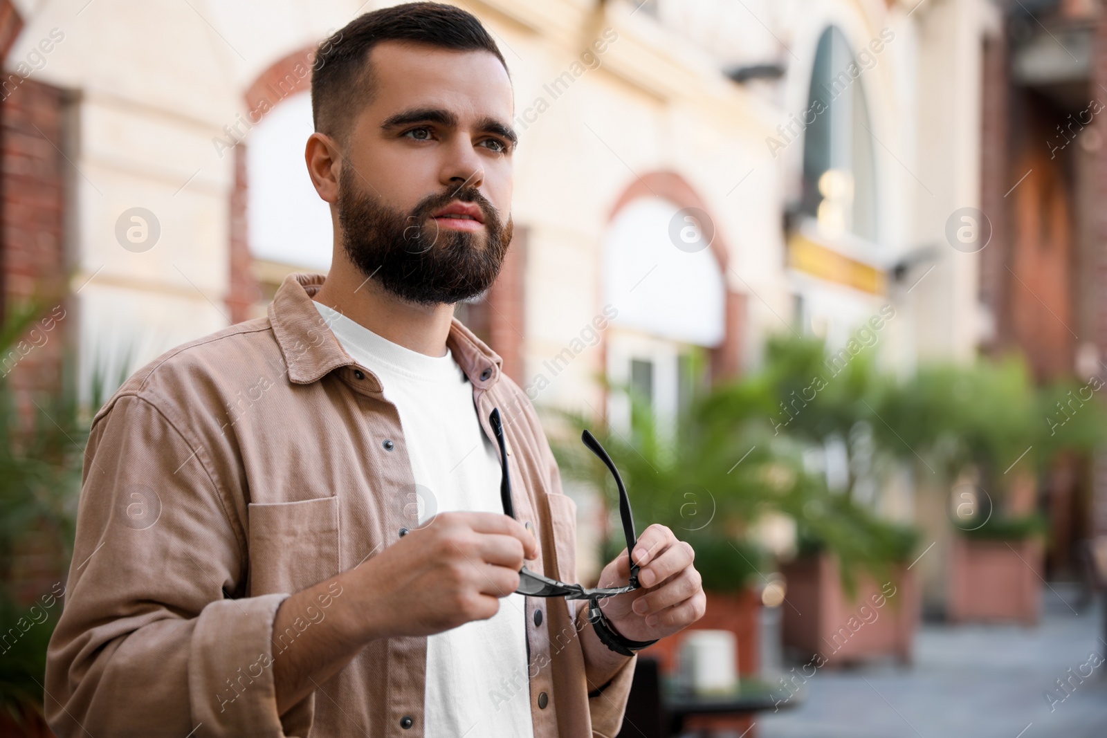 Photo of Portrait of handsome stylish man with sunglasses on city street. Space for text