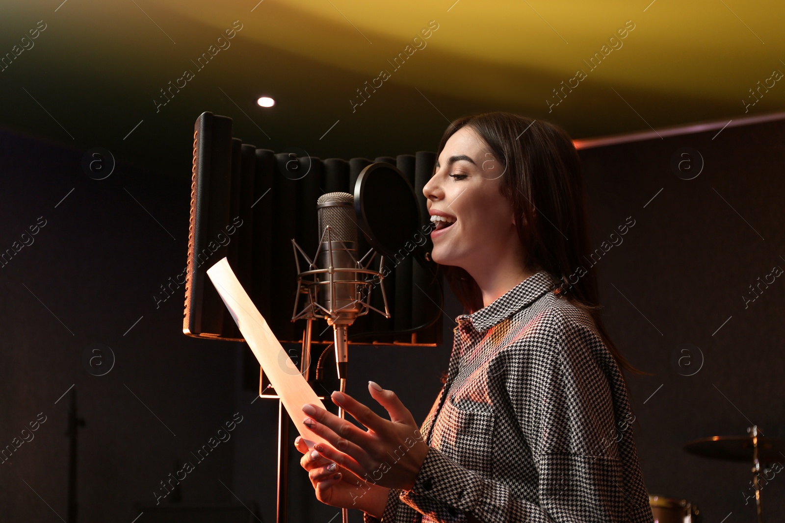 Photo of Young singer with microphone recording song in studio