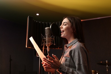 Photo of Young singer with microphone recording song in studio