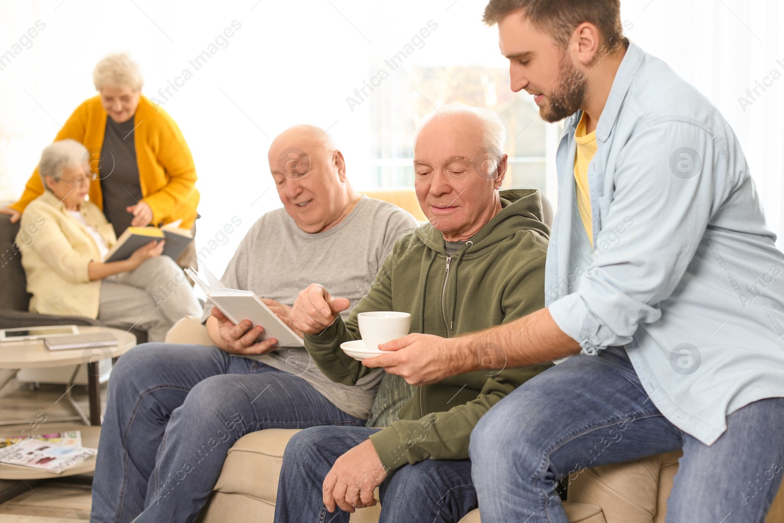 Photo of Young man taking care of elderly people in geriatric hospice