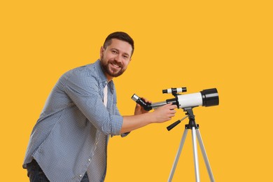 Photo of Happy astronomer with telescope on orange background