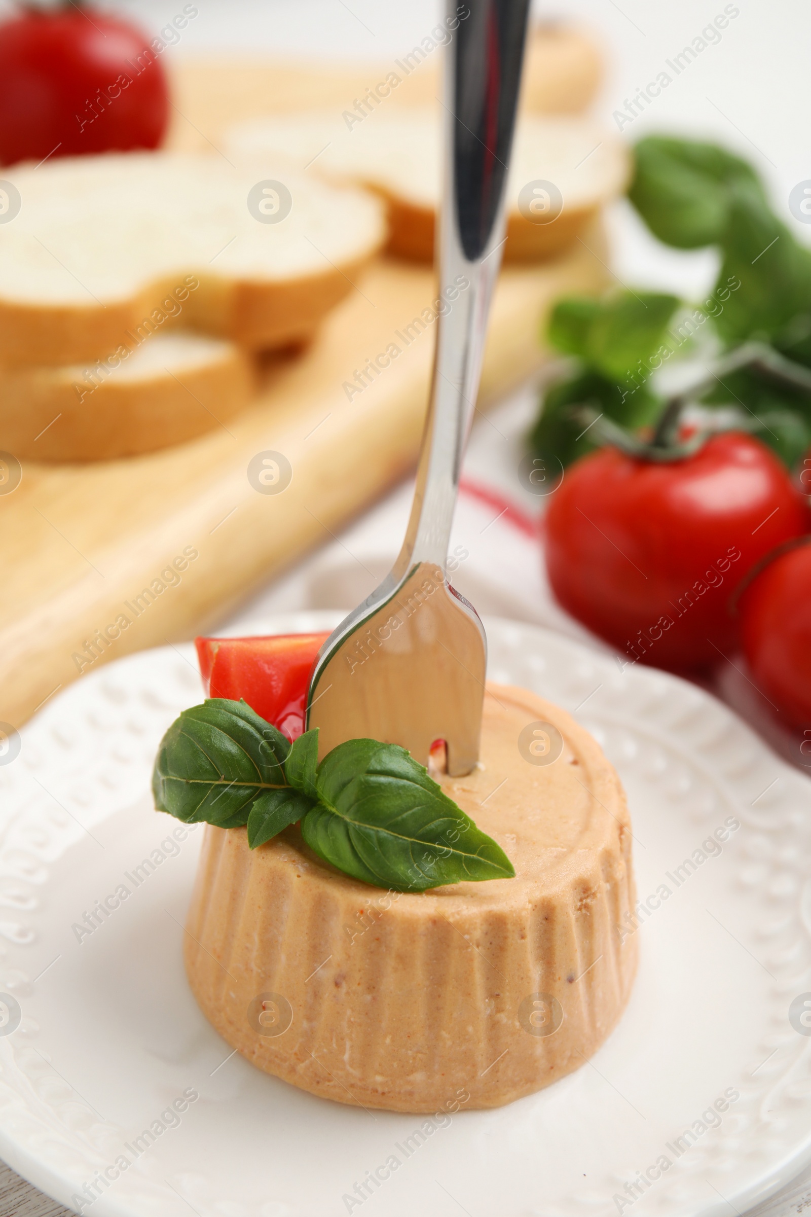 Photo of Delicious meat pate with basil and tomato served on table, closeup
