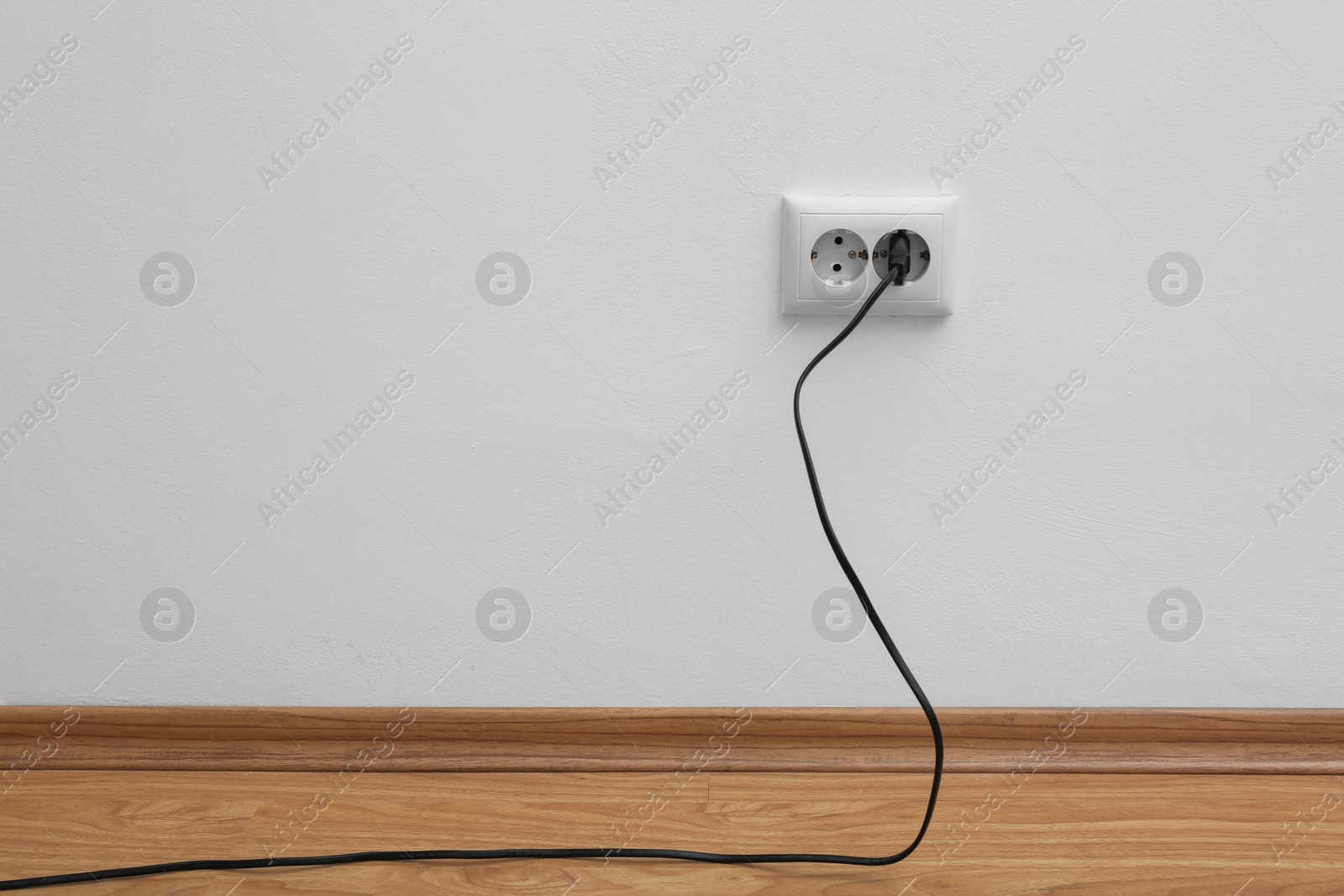 Photo of Power socket and plug on wall indoors, space for text. Electrician's equipment