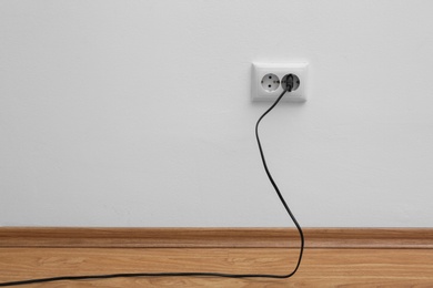 Photo of Power socket and plug on wall indoors, space for text. Electrician's equipment