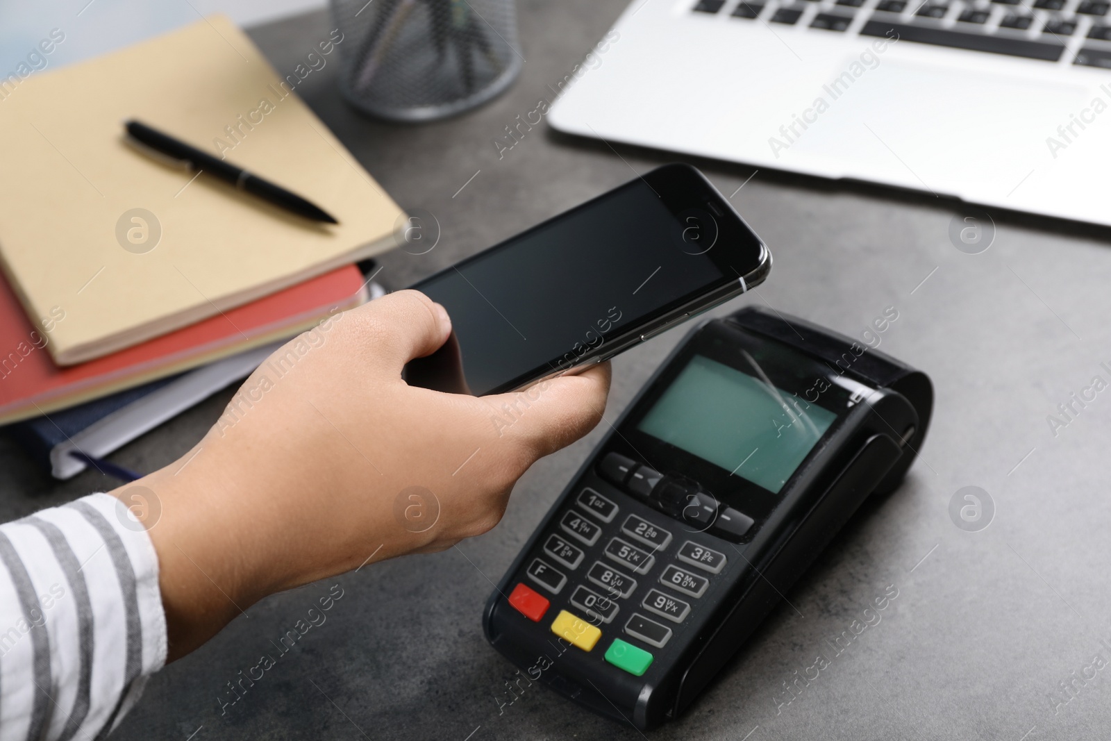 Photo of Woman using terminal for contactless payment with smartphone at table