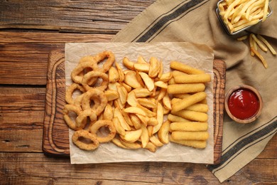 Different snacks and tasty ketchup on wooden table, flat lay