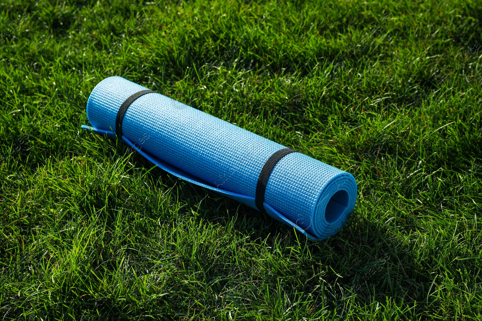 Photo of Bright exercise mat on fresh green grass outdoors