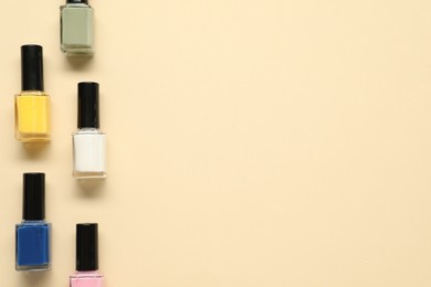 Bright nail polishes in bottles on beige background, flat lay. Space for text