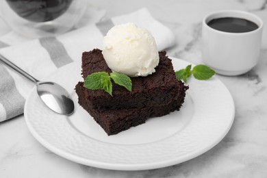 Tasty brownies with ice cream and mint served on white marble table, closeup