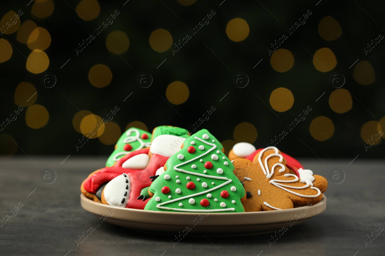 Photo of Decorated cookies on grey table against blurred Christmas lights