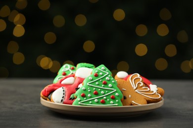 Photo of Decorated cookies on grey table against blurred Christmas lights