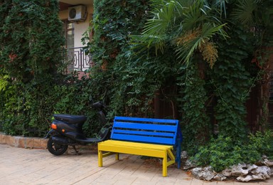 Beautiful blue and yellow wooden bench near scooter outdoors