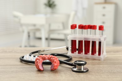 Photo of Endocrinology. Stethoscope, model of thyroid gland and blood samples in test tubes on table indoors