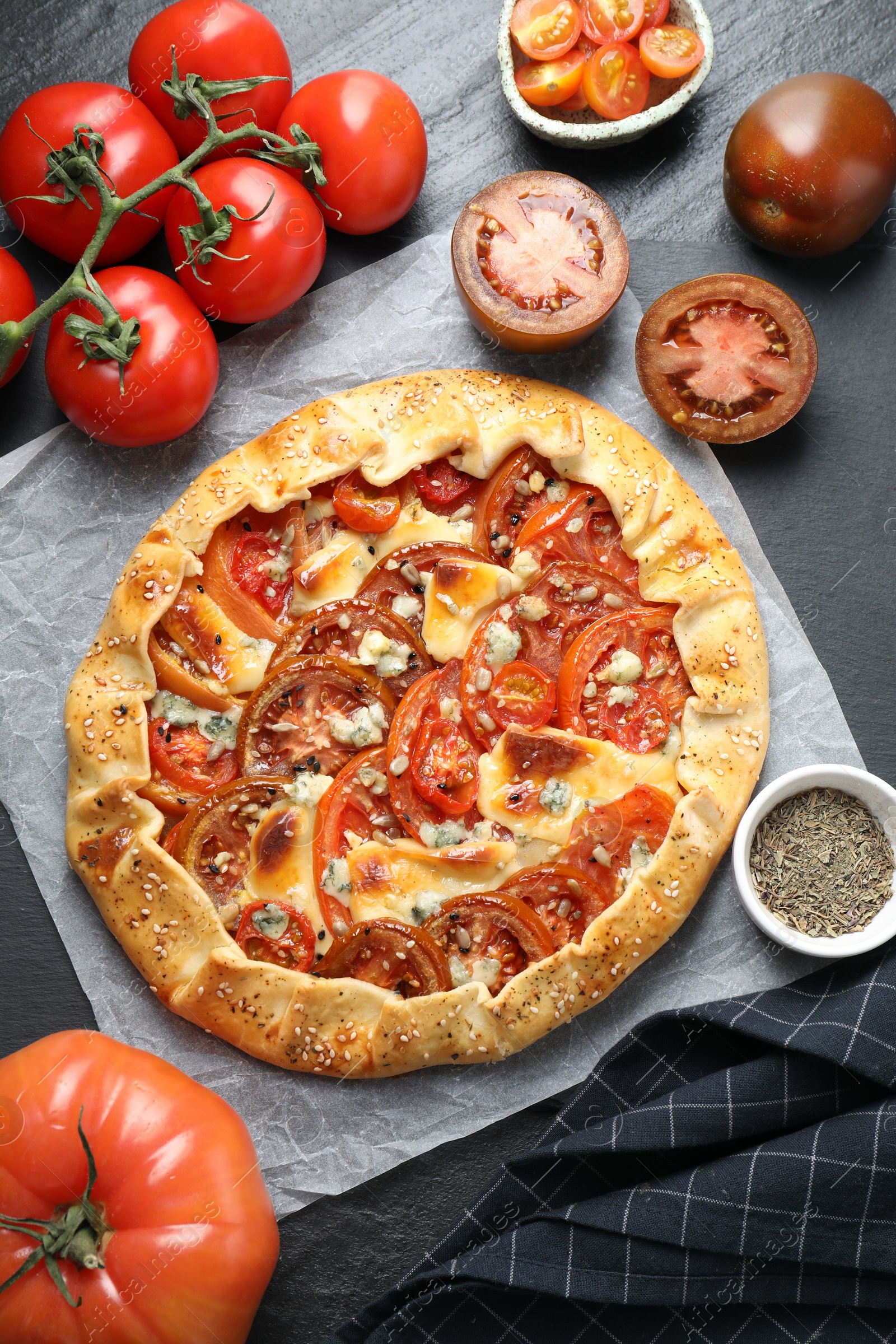 Photo of Flat lay composition of tasty galette with tomato and cheese (Caprese galette) on dark textured table