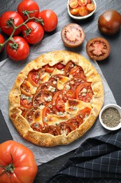 Flat lay composition of tasty galette with tomato and cheese (Caprese galette) on dark textured table