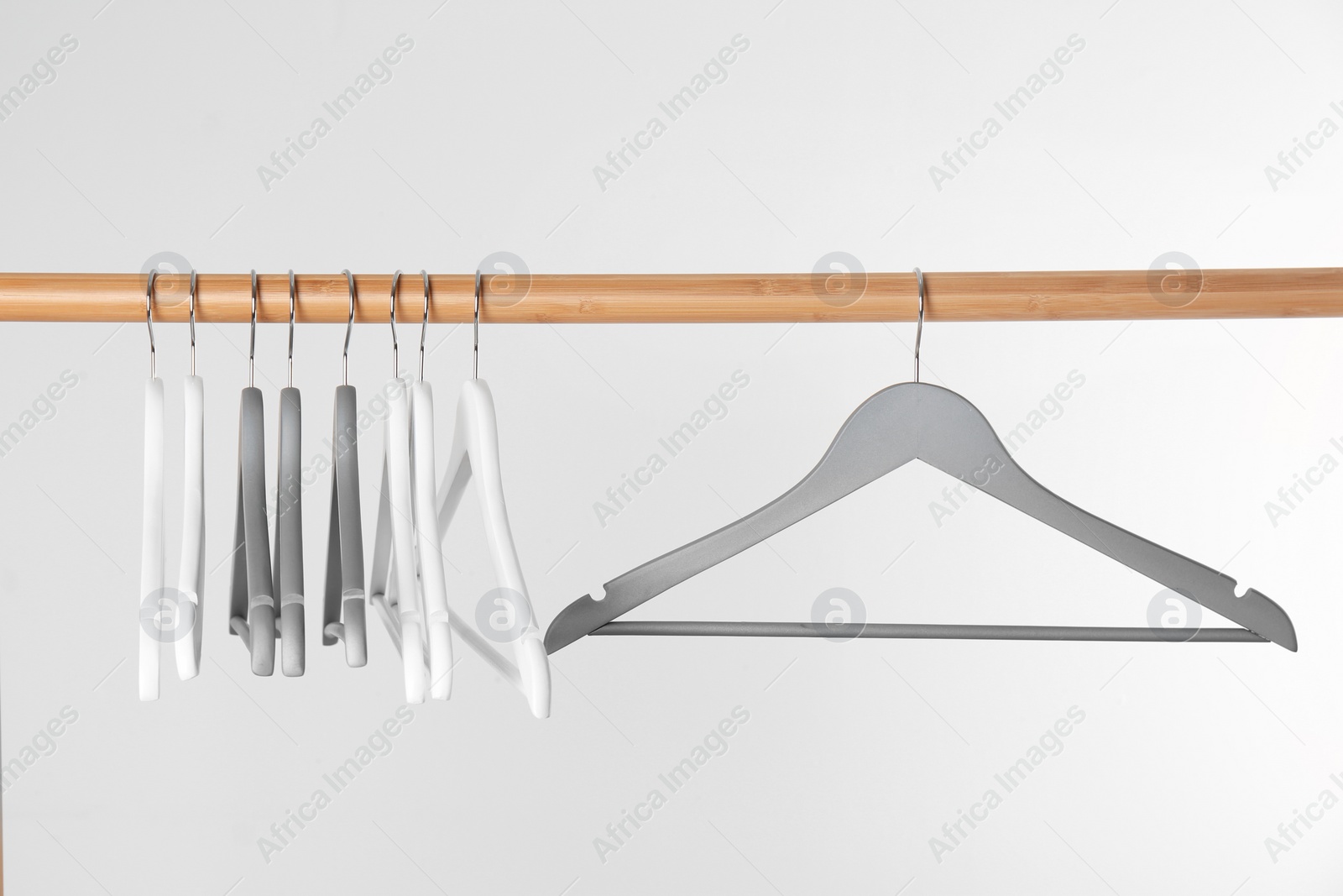 Photo of Wooden rack with clothes hangers on white background