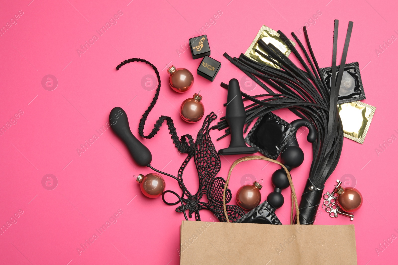 Photo of Shopping bag and different sex toys on pink background, flat lay