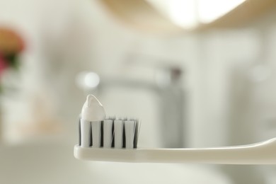 Photo of Brush with toothpaste in bathroom, closeup. Space for text