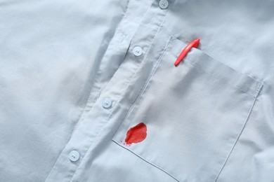 Photo of Pen and stain of red ink on light blue shirt, closeup
