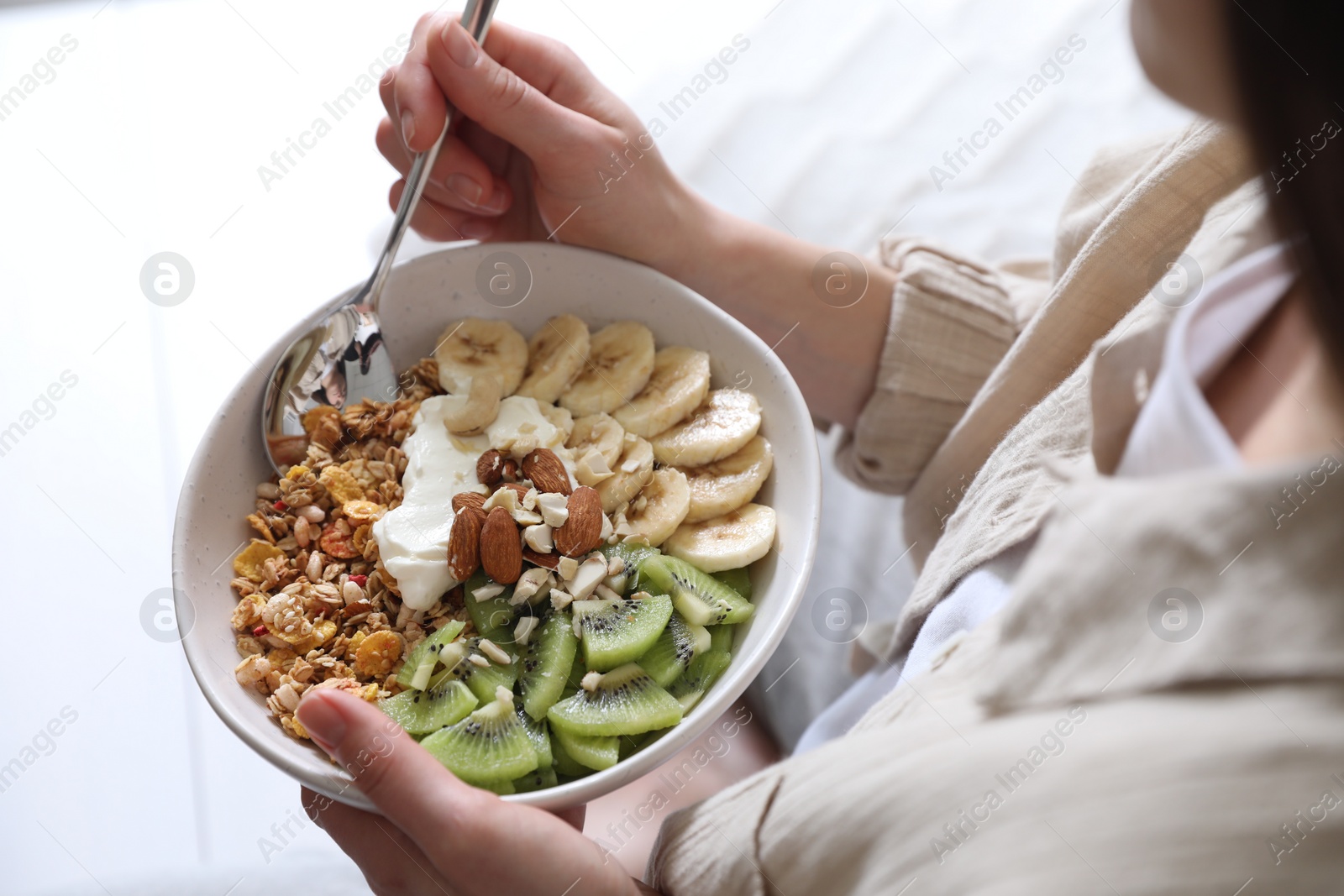 Photo of Woman eating tasty granola indoors, closeup view