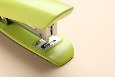 One bright stapler on beige background, closeup. Space for text