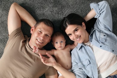 Happy family with their cute baby on floor, top view