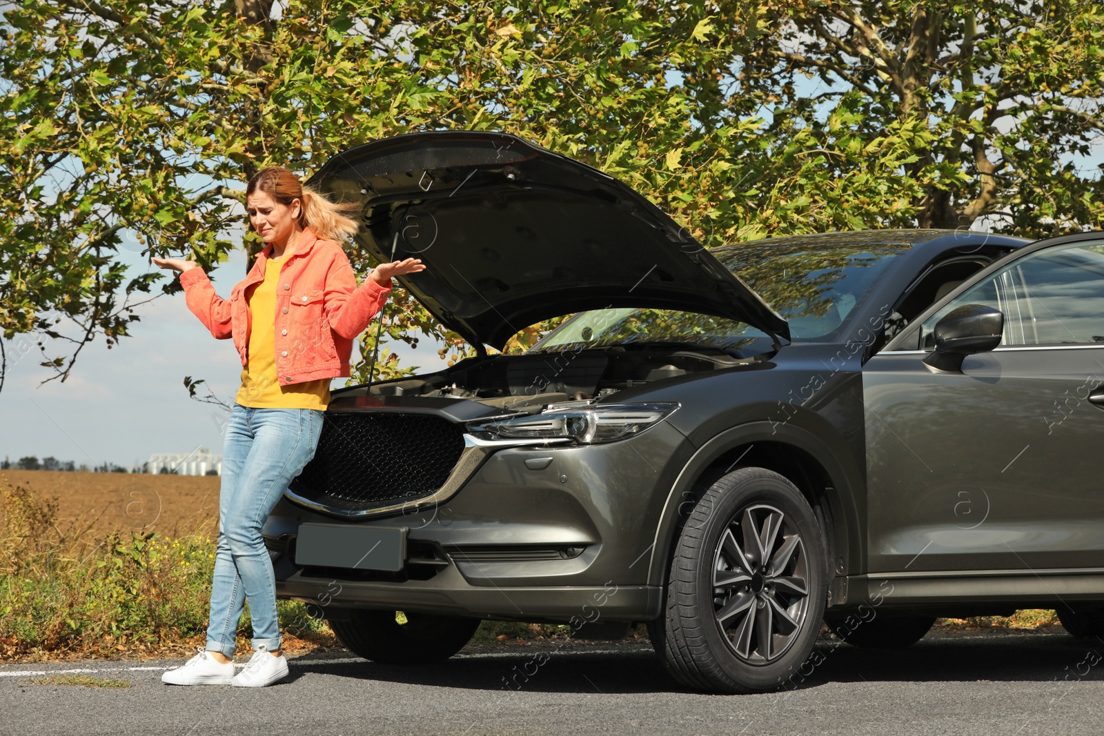 Photo of Woman near broken car on road. Auto insurance