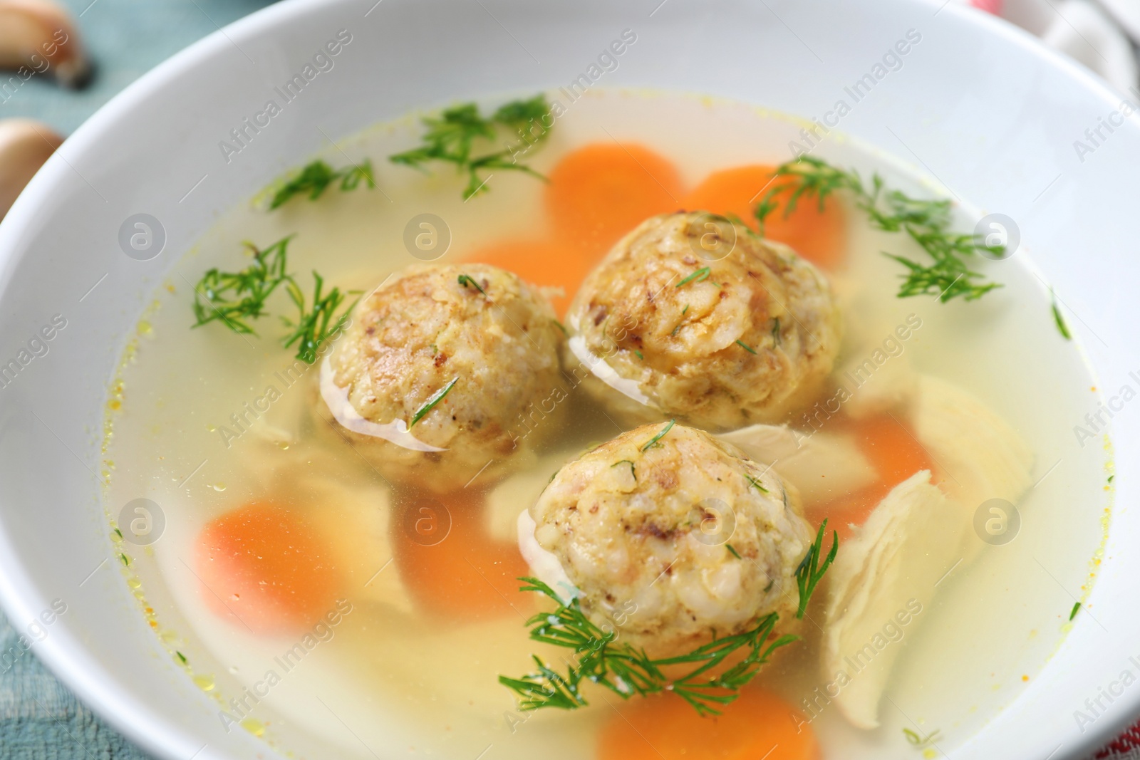 Photo of Bowl of Jewish matzoh balls soup on table, closeup