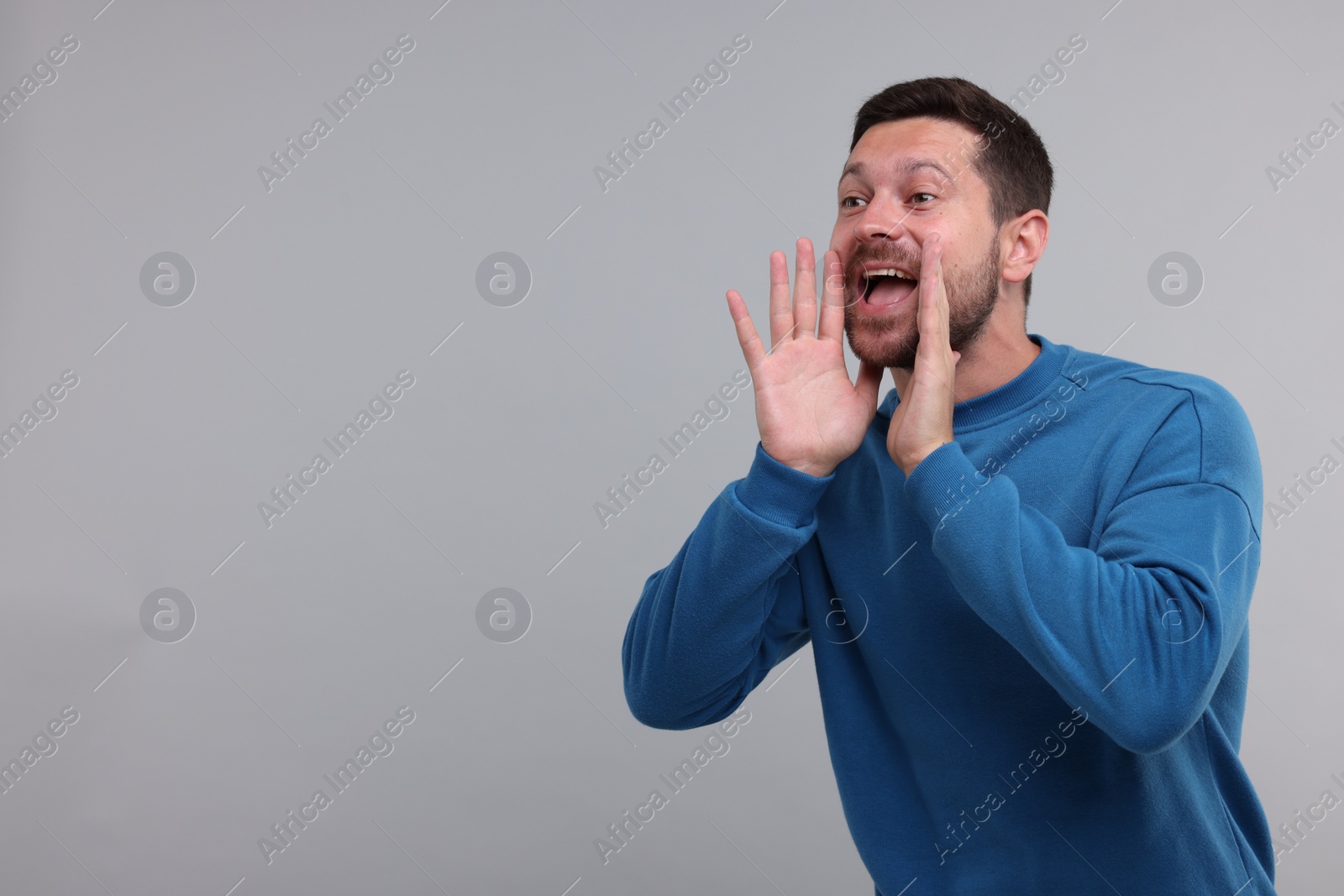 Photo of Special promotion. Man shouting to announce information on light grey background. Space for text