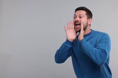 Photo of Special promotion. Man shouting to announce information on light grey background. Space for text