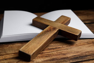 Photo of Christian cross and Bible on wooden background, closeup. Religion concept