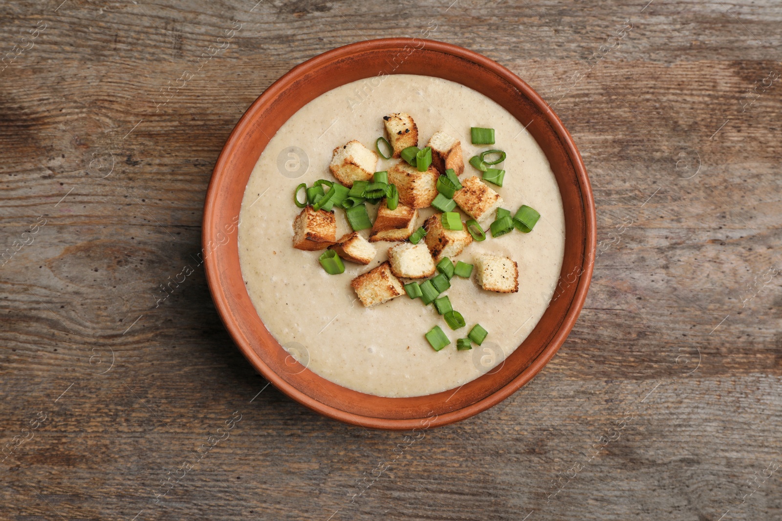 Photo of Bowl of fresh homemade mushroom soup on wooden background, top view