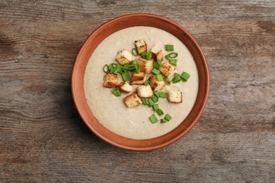 Photo of Bowl of fresh homemade mushroom soup on wooden background, top view