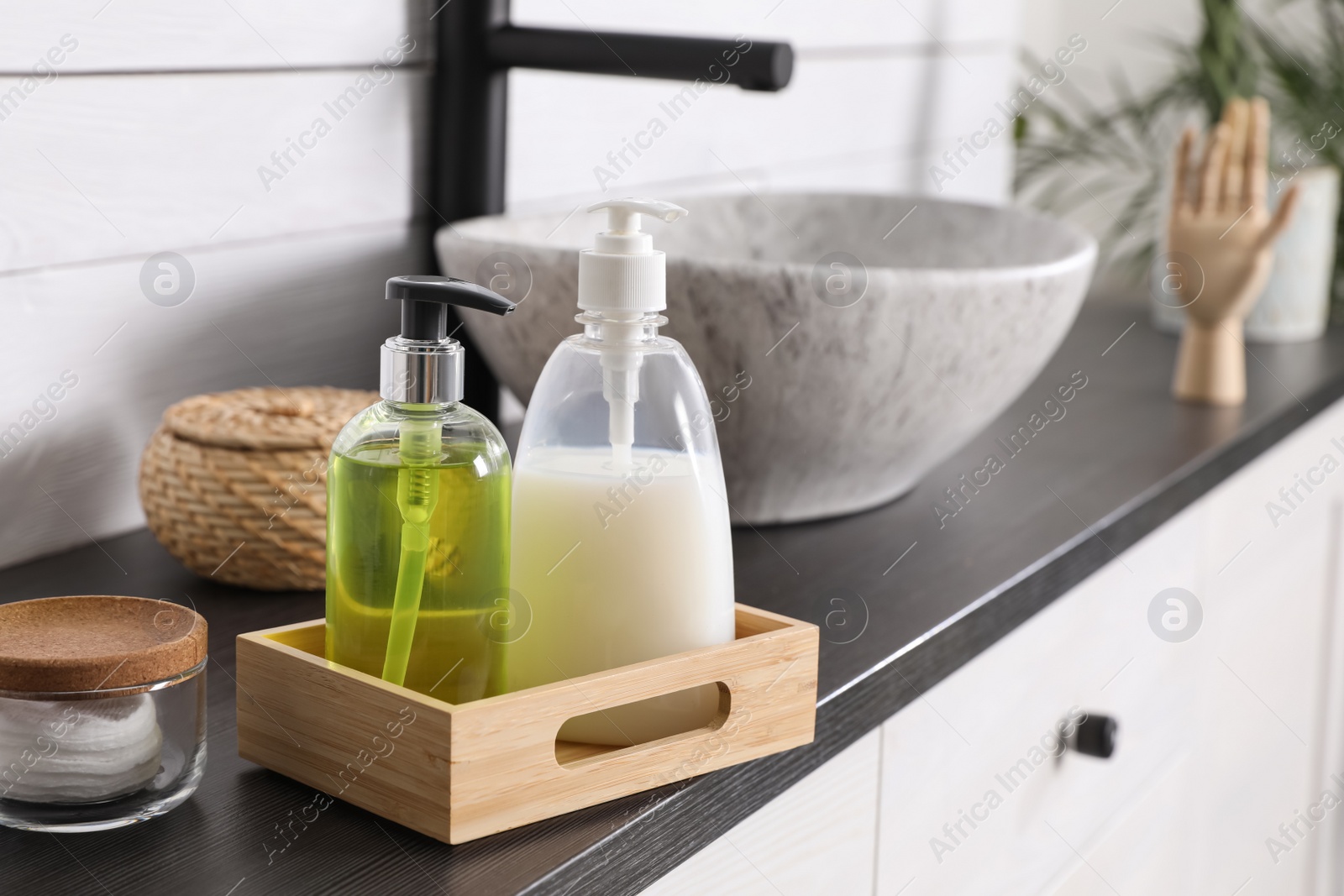 Photo of Dispensers with liquid soap on countertop in bathroom