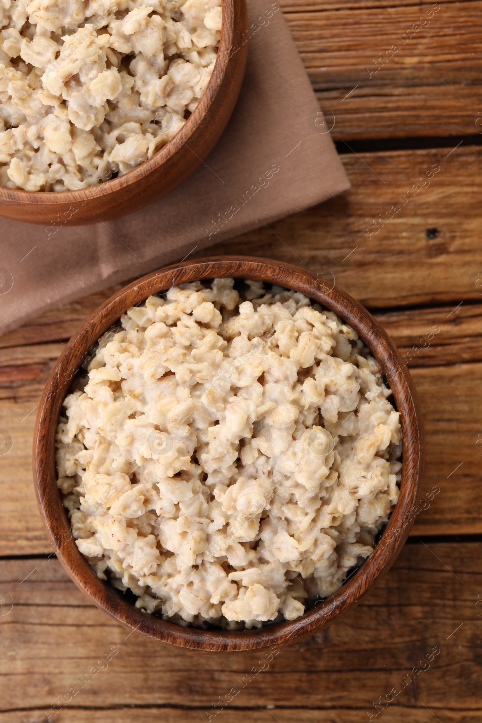 Photo of Tasty boiled oatmeal on wooden table, flat lay