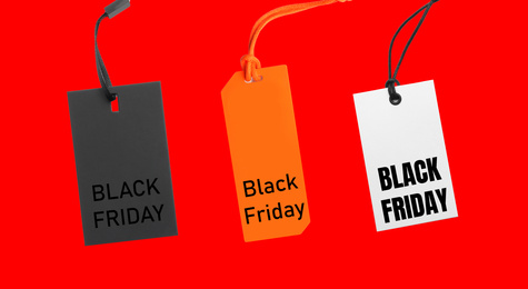 Different tags with text BLACK FRIDAY on red background, flat lay 